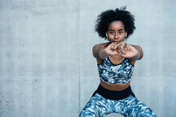Afro athletic woman stretching arms before exercise.