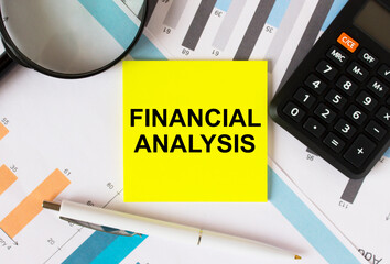 Yellow sticker with text Financial Analysis with calculator white pen magnifying glass on the diagrams