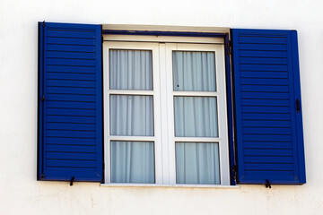 closed window with blue shutters, on white wall