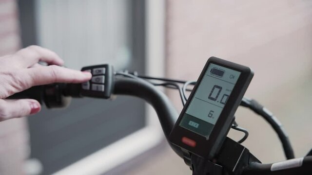 Woman adjusts the speed compensation on  a E-bike with the controls on the handle bar.
