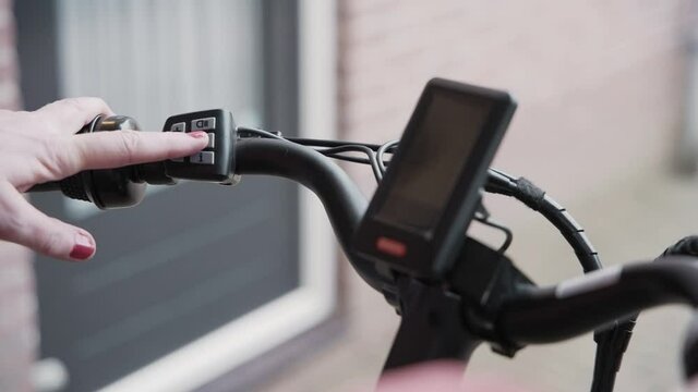 Close up of the handle bars of a e-bike as a male and female figure out how to turn it on using the controls on the handle bar.
