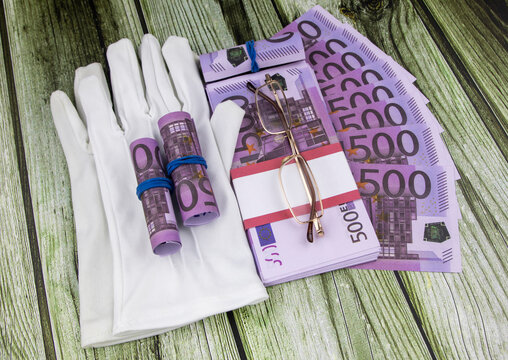 Financial or business concept with a pair of white gloves, eyeglasses and wads and fanned 500 Euro banknotes with colorful circular memo pads over a white marble background in a flat lay view