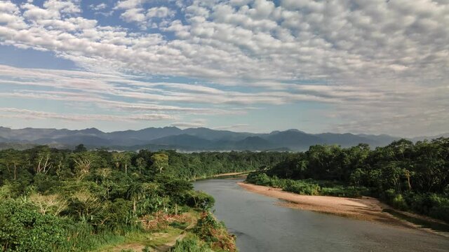 Hyperlapse aerial shot over Misahualli River surrounded by rainforest and trees during sunny day. Tena, Ecuador.