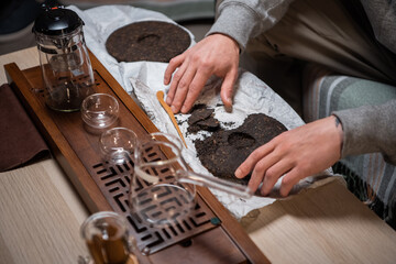 A man bought a set of milking tea ceremony at home and breaks off a piece of raw puerh tea cake with a needle to brew a strong fragrant tea.