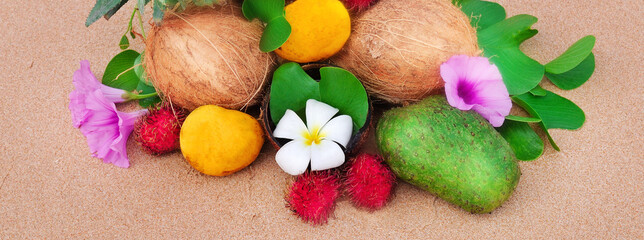 Tropical fruit on a sandy beach. Wide photo.