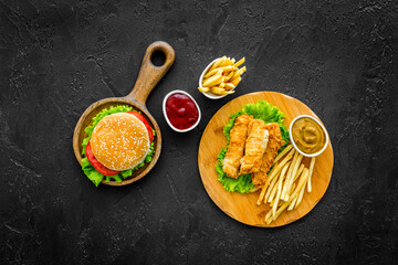 Classic burger served on wooden cutting board with french fries and fried chicken