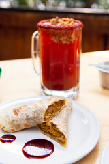 Mexican burrito and michelada beer with tomato juice with copy space. Michelada beer with tomato juice and burritos. Mexican food on wooden table. Concept of traditional food and mexican drink.