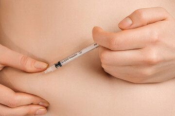 The woman is injecting herself with insulin from the fat layer on her abdomen.