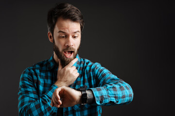 Bearded white shock man exclaiming while looking at his wristwatch
