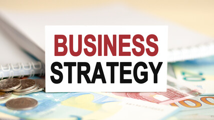 on the table are banknotes, coins and a sign that says - business strategy, financial and economic concept.