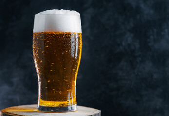 Pint glass of cold light beer on a dark table with copy space