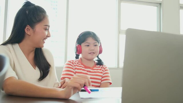 Asian mother enjoy teach and explain homework to child daughter for online study during homeschooling at home ,home quarantine, online learning new normal lifestyle
