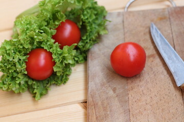 tomatoes greens and legs on a wooden background.