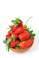 Group of fresh strawberries in the clay bowl, isolated on a white background