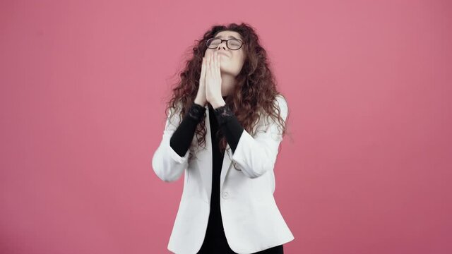 The young woman with curly hair, with crossed hairs, makes a wish, asking to be fulfilled. Young hipster in white jacket and black shirt,