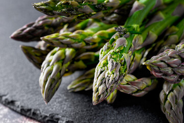 Close up of tips from a bunch of green asparagus. Placed on a black slate plate.