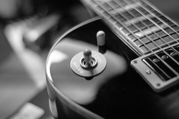 Czarno białe zdjęcie, zbliżenie na gitarę. Struny i przełączniki - detale instrumentu muzycznego