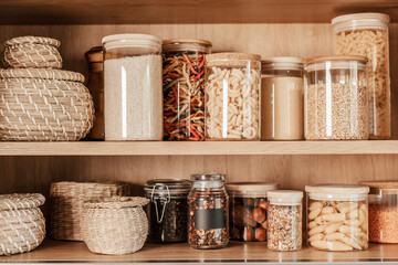 Organizing zero waste storage in the kitchen. Pasta and cereals in reusable glass containers in kitchen shelf. Sustainable lifestyle idea - obrazy, fototapety, plakaty