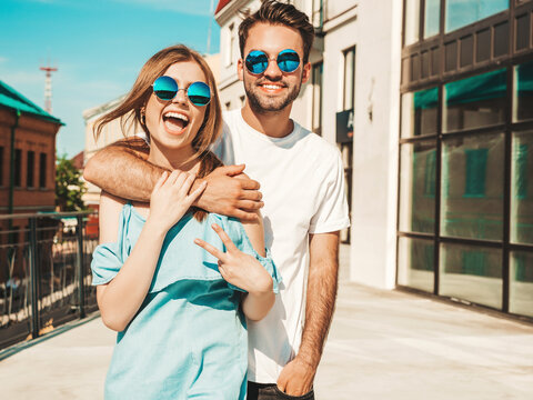 Portrait of smiling beautiful woman and her handsome boyfriend. Woman in casual summer jeans dress. Happy cheerful family. Female having fun. Couple posing on the street background in sunglasses