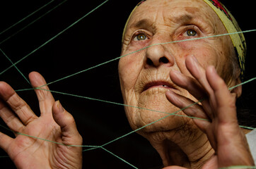 Grandma's wrinkled face. The man is entangled in the threads. Manipulation. Be under pressure....