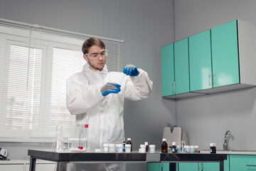 Pipette in hand. Technician in blue gloves pouring something into the test tube and looking busy
