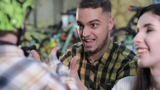Happy little boy shows thumb-up and gives five to parents choosing bike and equipment in contemporary sports shop close view