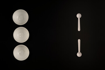 White cups and white spoons on black background