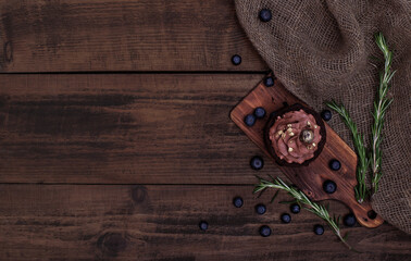 Gluten free cake with blueberry and carob. Homemade chocolate cake with berries and rosemary on brown wooden background with burlap cloth. Cacao sponge cake. Top view, copy space