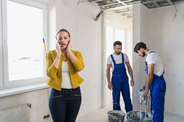Inspector calls on the phone, workers knead plaster