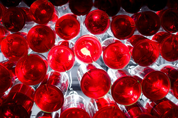 the bottoms of bottles of red liquid hang from the ceiling and illuminate the wine cellar with decorative lighting a bottle chandelier.