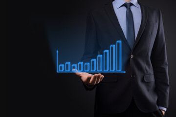 Business man holding holographic graphs and stock market statistics gain profits. Concept of growth planning and business strategy. Display of good economy form digital screen.