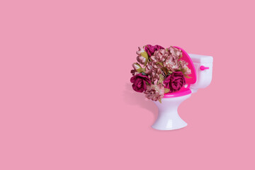 Creative funny idea made of toilet bowl with many colorful flowers on a pink background.
