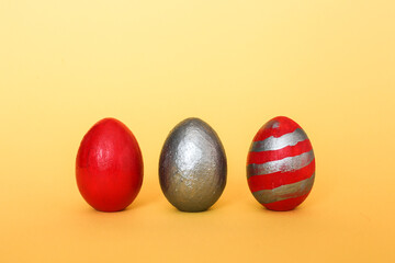 Three multi-colored decorative freshly painted eggs on a yellow background. Colored easter eggs on a light background