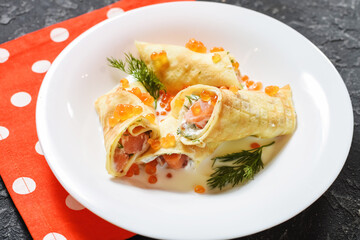 Delicious breakfast - crepes with smoked salmon, sour cream and caviarch on stone background.