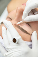Zbliżenie na proces makijażu permanentnego. Kobieta w salonie urody w trakcie zabiegu pigmentacji brwi.  - obrazy, fototapety, plakaty