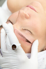 Zbliżenie na proces pigmentacji brwi. Zaczerwienie skóry w trakcie zabiegu, makijaż permanentny. 