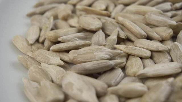 Peeled uncooked sunflower seeds in a white plate. Macro. Dolly Shot