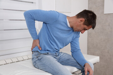 Male patient suffering from back pain waiting for medical exam at the doctor's office