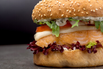 Tasty burger with salmon and vegetables coseup