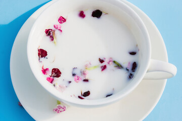 White Cup with vegan milk and flowers on a blue background. Concept of vegetarian drinks and food, herbal teas, beauty and health, Spa