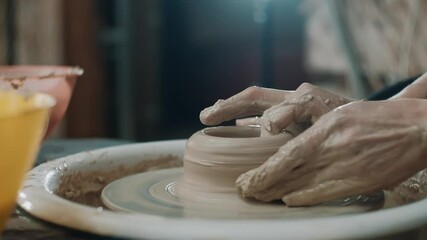 Female potter sitting and makes a pot on the pottery wheel. Woman making ceramic item.Pottery working, handmade and creative skills