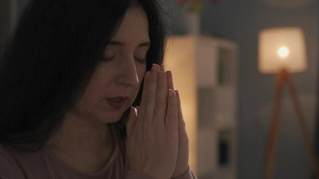 Woman praying to God at home. 