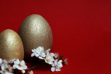 golden eggs and flowering branch on red background easter concept, copy space