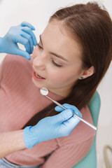 Vertical top view shot of a young woman getting dental checkup by unrecognizable dentist