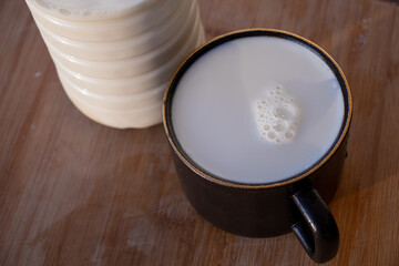 Glass of milk standing on old wooden table. Black glass with white milk. Black glass with white milk on the table