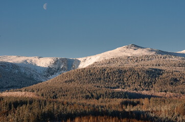 Zimowy mroźny poranek w górach z widocznym jeszcze zachodzącym księżycem.