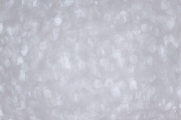 Abstract silver blurred background with numerous colourful bright festive bokeh. Texture with copy space for text. Celebration, holidays concept. Horizontal. Soft selective focus