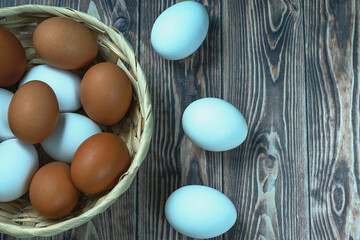 several fresh chicken eggs in a straw basket on a wooden background. Healthy eating concept