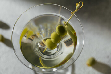 Glass of classic dry martini cocktail with olives on grey stone background