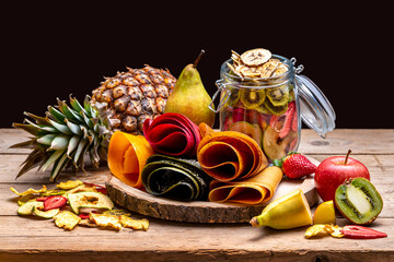 Multicolored fruit marshmallow rolled into rolls on a black background and fruits 